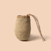 Woven straw bag with drawstring on a beige background