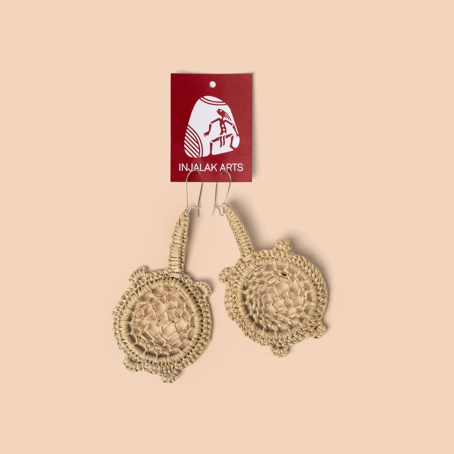Pair of beaded earrings with 'Inujalak Arts' tag on a beige background