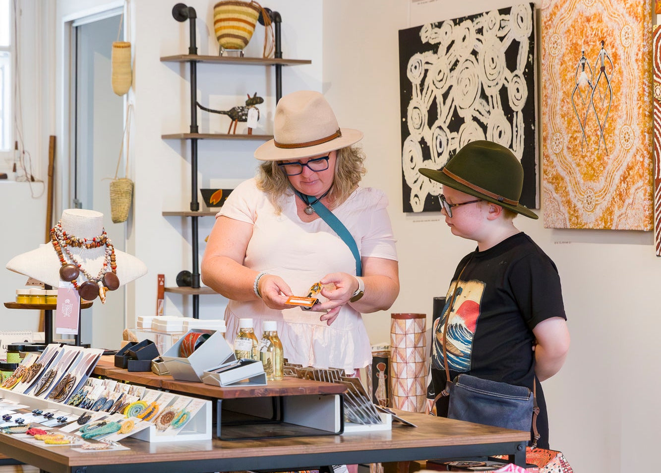 Two people in a store with various items on display, including books and clothing.